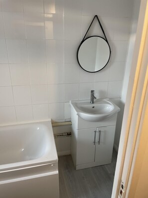 A bathroom with a white sink, a mirror, and a bathtub.