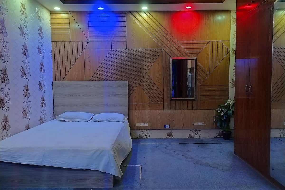 Une chambre à coucher avec un lit, un lambris en bois, un miroir et une porte.