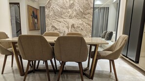 A modern dining area with a marble wall, a painting, and a view of a staircase. - Hotel Nyzote Inn (Dhaka)
