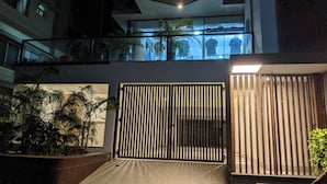 A modern building with a gated entrance, potted plants, and a balcony with a view of the cityscape. - Hotel Nyzote Inn (Dhaka)