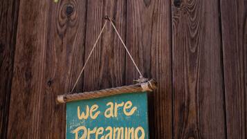 A rustic wooden wall with a hanging sign that reads "we are dreaming."
