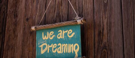 A rustic wooden wall with a hanging sign that reads "we are dreaming."