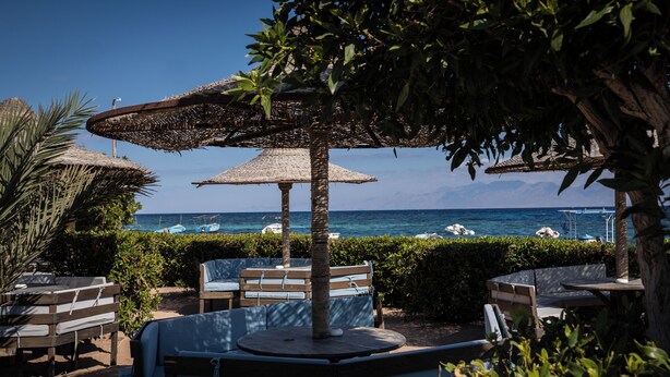 A beachside seating area with umbrellas, benches, and a view of the ocean. - Eldorado Lodge & Restaurant (Dahab)