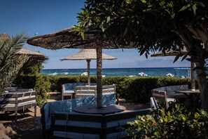 A beachside seating area with umbrellas, benches, and a view of the ocean. - Eldorado Lodge & Restaurant (Dahab)