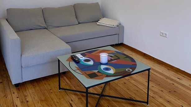 A room with a grey sofa, a coffee table with a colorful geometric design, and a hanging light fixture. - Modern, Centrally Located Apartment (Thessaloniki)