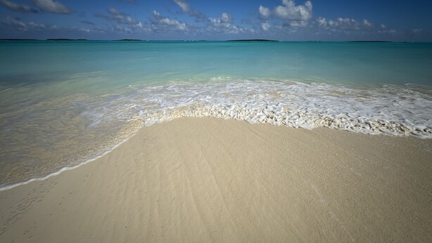 A beach with clear turquoise water and a sandy shore. - Rolleville Darling House 1 Bedroom Unit (Rolleville)