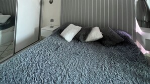 A bedroom with a bed, a mirror, and a ceiling light fixture. - MERDZ Spa & Fitness Sky Resident  (Skopje)