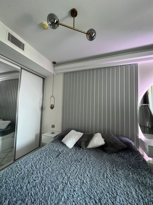 A bedroom with a bed, a mirror, and a ceiling light fixture.