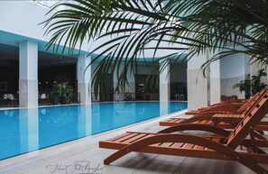 A pool area with lounge chairs and palm trees.