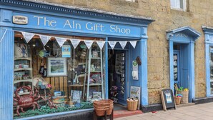 Une boutique avec un auvent bleu et une enseigne sur laquelle on peut lire : « The Aln Gift Shop ».