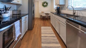 A modern kitchen with stainless steel appliances, a wooden floor, and a striped rug. - 4 BR Sleeps 10 Near UGA & Downtown (Athens)