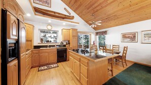 A spacious kitchen with wooden cabinets, a central island, and a dining area with chairs.