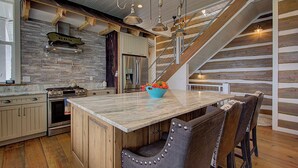A modern kitchen with a central island, wooden accents, and a built-in stove. - 6BD, 5 Bath - Mountaintop Mansion in the Sky (Tellico Plains)