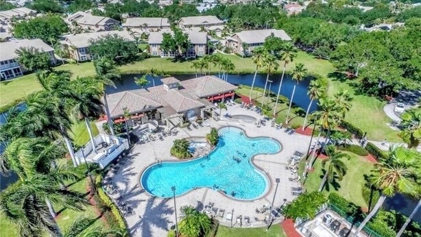 Luchtbeeld van een resort met een groot, kronkelend zwembad, omringd door palmbomen en ligbedden.