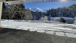 Un paysage enneigé avec une montagne en arrière-plan, une structure en bois et un ciel dégagé.