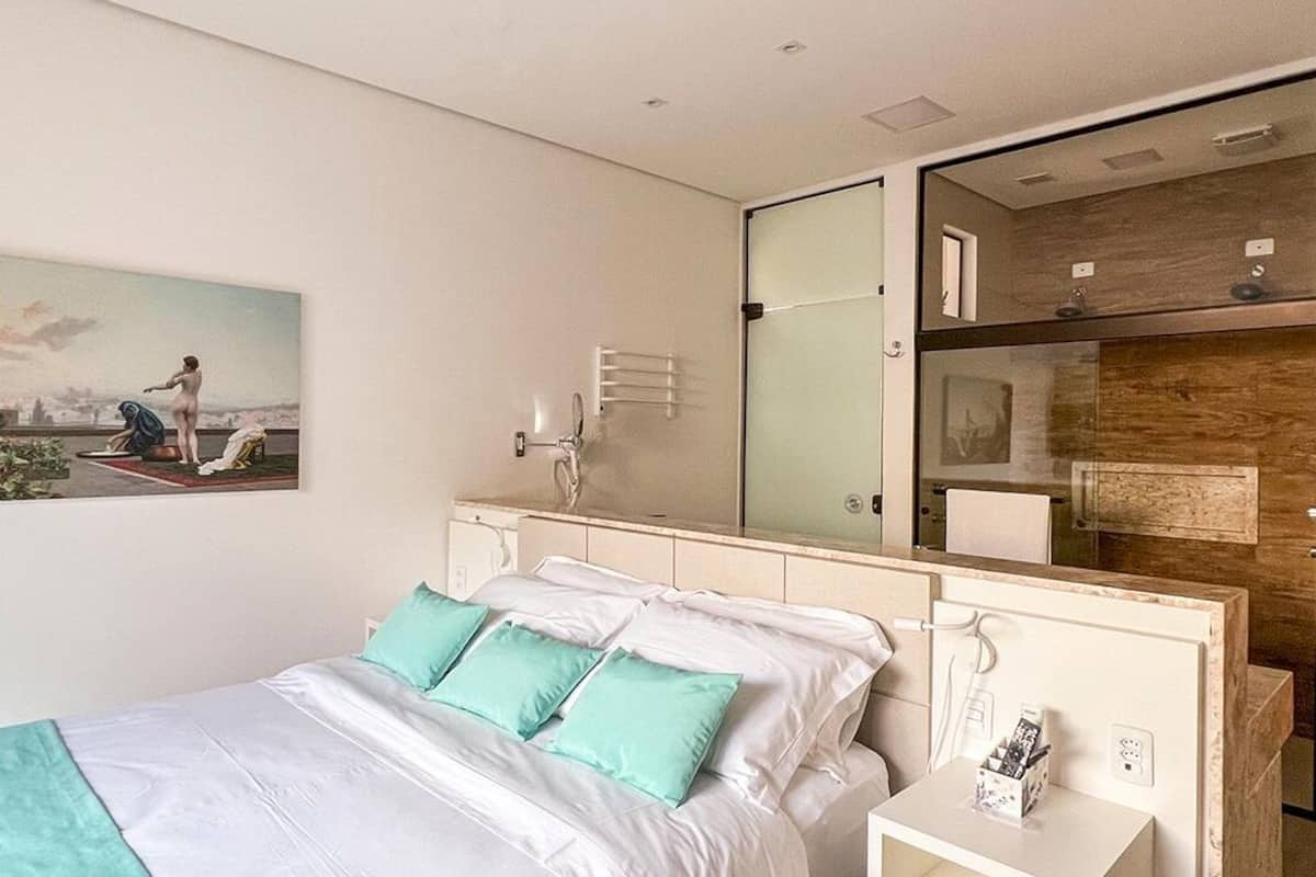 A modern bedroom with a large bed, a nightstand, a mirror, and a cityscape painting on the wall.