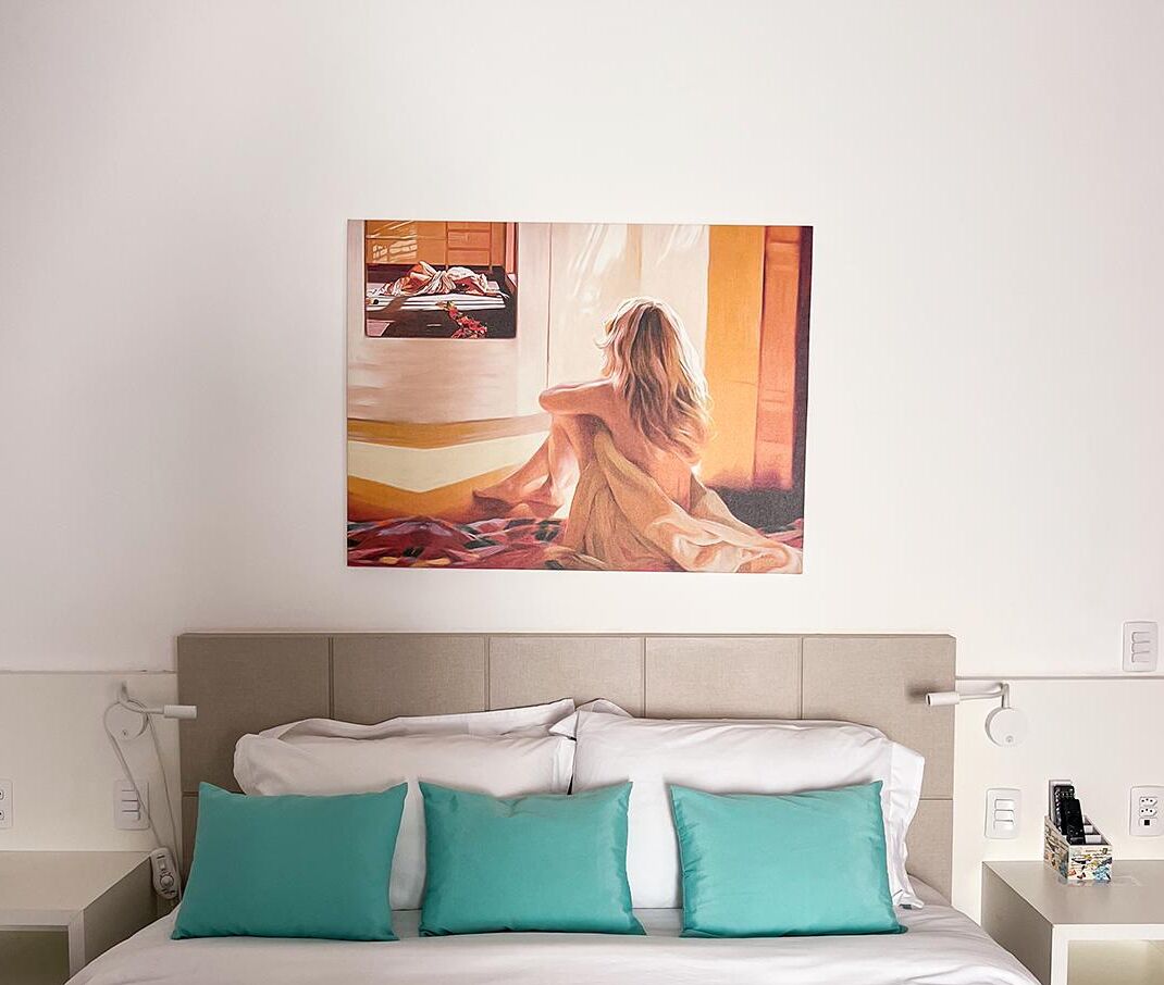 Quarto com cama, almofadas azul-turquesa, mesa de cabeceira e um quadro na parede.
