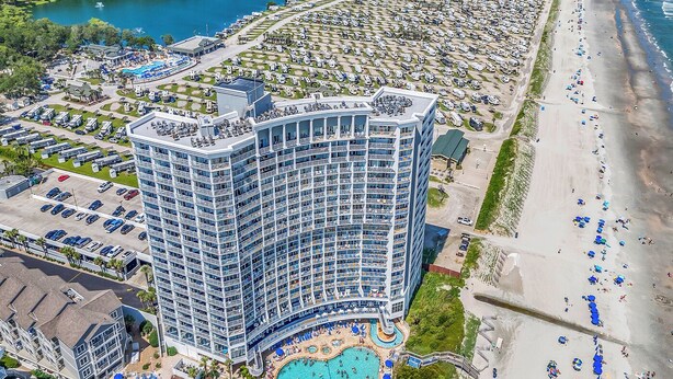 A high-rise hotel with multiple balconies, a pool area, and a beachside location. - Oceanfront Updated Condo at SeaWatch Resort 6 Pools 10 Hot Tubs Balcony King Bed (Myrtle Beach)