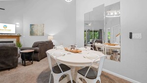 Una sala de estar moderna con comedor, chimenea y un espejo grande que refleja la habitación.