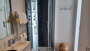 Une salle de bain moderne avec une douche à parois de verre, un lave-linge encastré et un miroir au-dessus du lavabo.