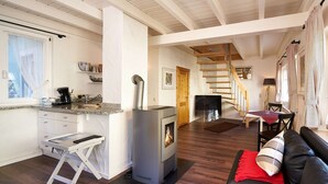 A modern living space with a kitchen, a fireplace, a staircase, and a cozy seating area.