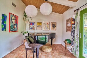Una habitación con un piano de cola, un banco y varias obras de arte enmarcadas en las paredes.