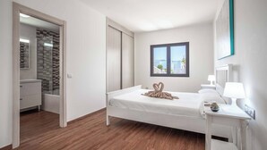 Un dormitorio moderno con cama, mesita de noche y ventana.