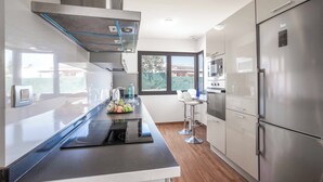 Una cocina moderna con un refrigerador de acero inoxidable, horno integrado y encimera negra.