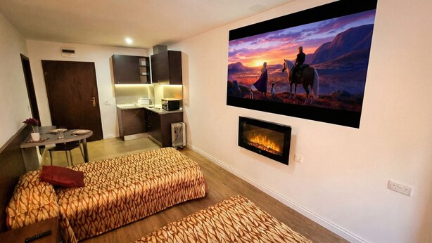 A hotel room with a bed, a small desk, a TV, and a fireplace. - Mountain Paradise 2 - Quiet Cosy Studio - Balcony, Wifi (Bansko)