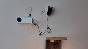A wall-mounted projector with a wooden shelf below, connected to a power outlet. - Mountain Paradise 2 - Quiet Cosy Studio - Balcony, Wifi (Bansko)