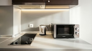 A modern kitchen with a built-in induction cooktop, a kettle, and a microwave. - Mountain Paradise 2 - Quiet Cosy Studio - Balcony, Wifi (Bansko)