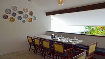 A dining area with a long table set for six, surrounded by wooden chairs with woven seats.