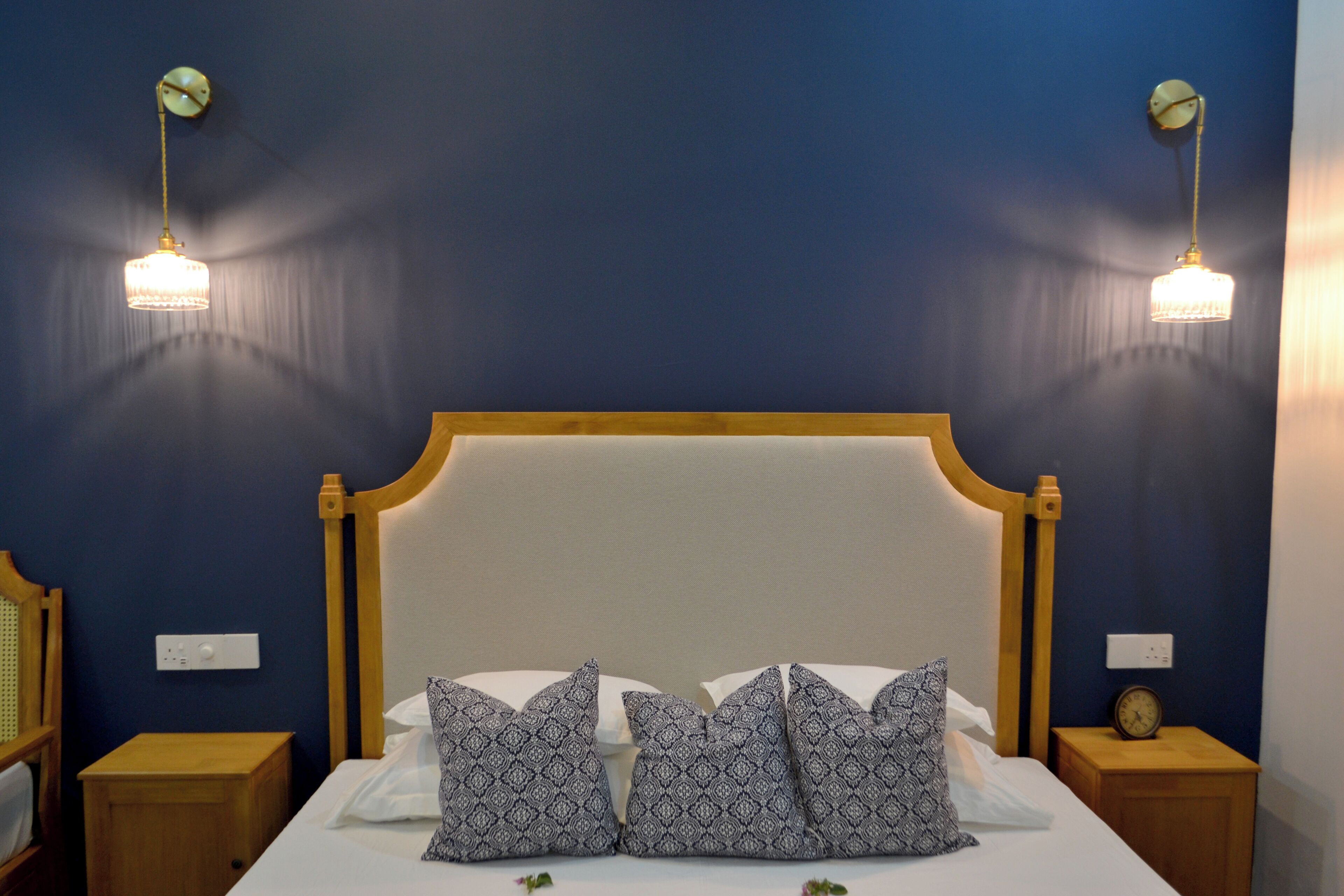 A neatly made bed with patterned pillows, a wooden headboard, and two bedside tables with lamps.