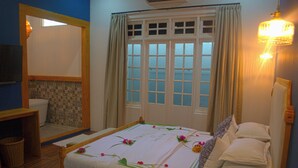 A bedroom with a bed, a mirror, a window with curtains, and a wall-mounted light fixture. - Athirige Boutique House (Dharavandhoo)