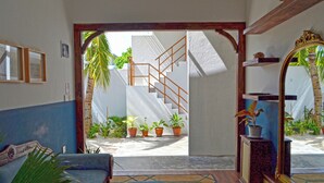 A room with a blue sofa, a wooden coffee table, a mirror, and a staircase leading to an outdoor area with potted plants. - Athirige Boutique House (Dharavandhoo)