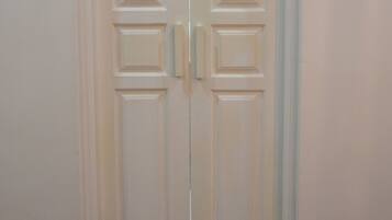 Puerta doble blanca con un interruptor de luz en la pared a la izquierda.