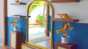 A room with a wooden floor, a large mirror with a golden frame, and two potted plants on wooden stands. - Athirige Boutique House (Dharavandhoo)