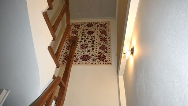 A wooden staircase with a patterned carpet at the bottom.