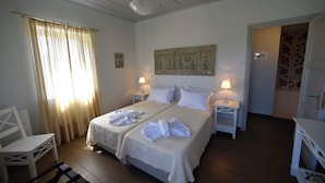 A hotel room with two beds, a sitting area with a chair, and a small table.