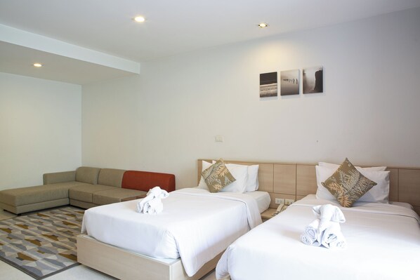 Relax in this stylish room with two single beds, a comfortable sofa, and a geometric-patterned rug.
