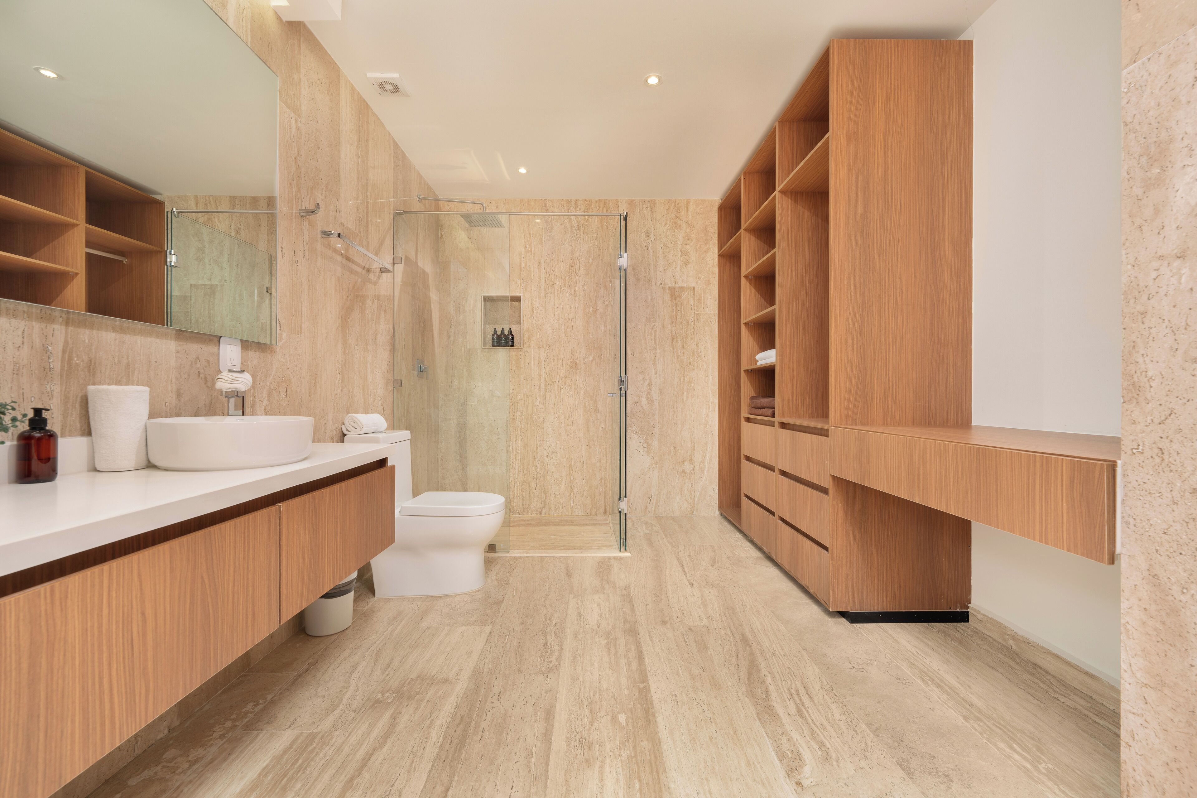 A modern bathroom with a large mirror, wooden vanity, and a glass-enclosed shower.