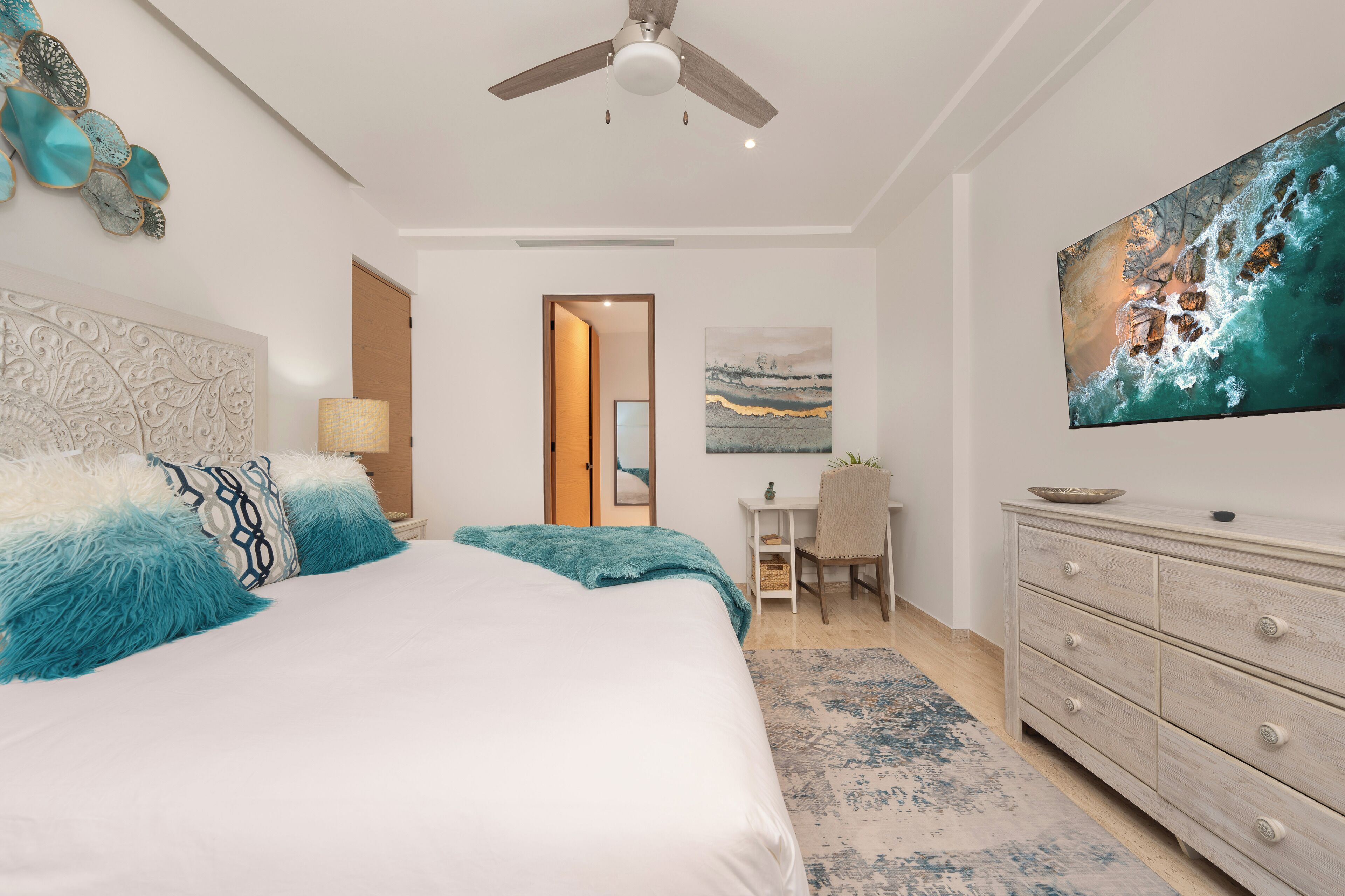 A bedroom with a bed, a desk, and a dresser.