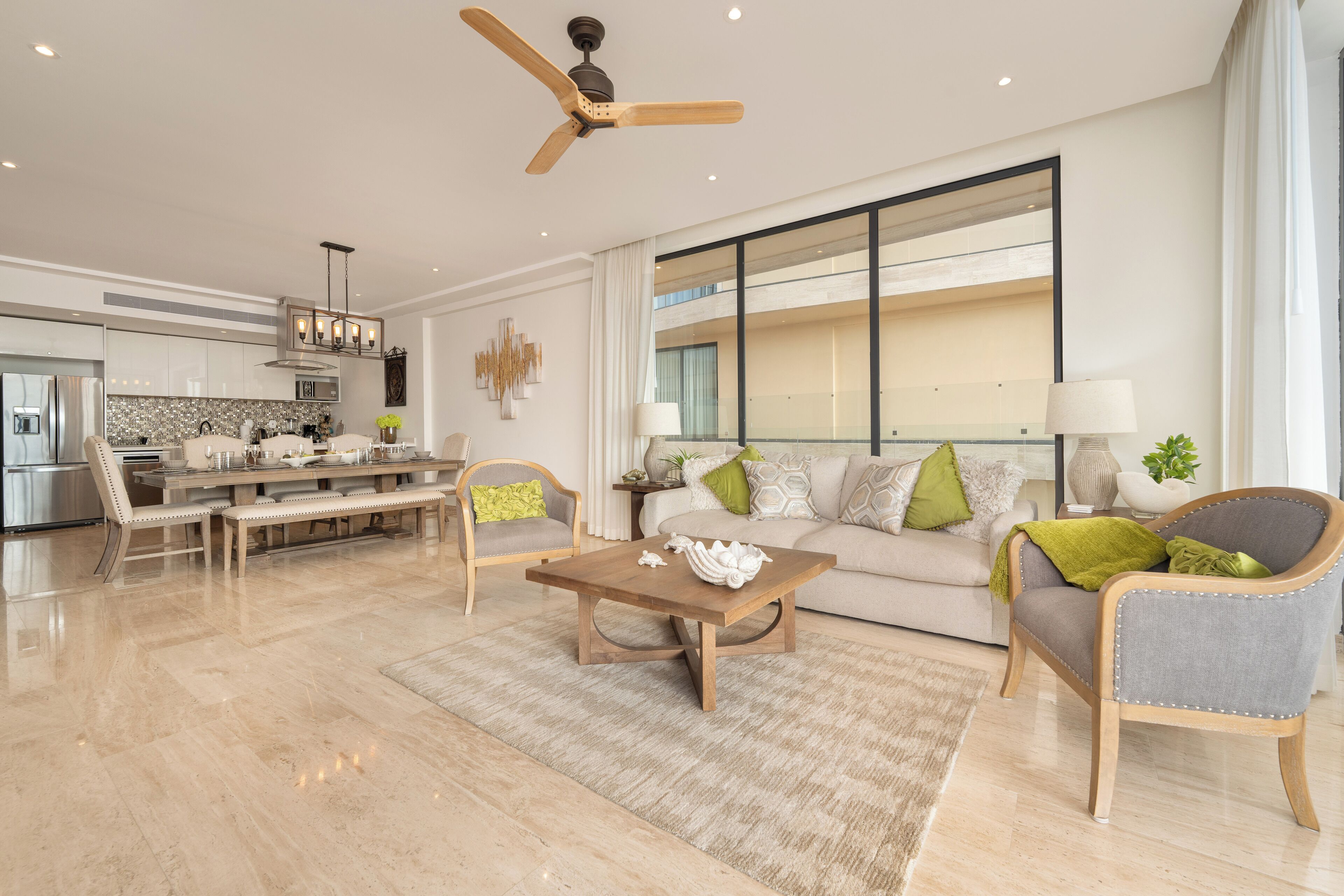 A modern living room with a dining area, a large window, and a ceiling fan.
