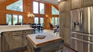 Eine geräumige Küche mit Holzwänden, großen Fenstern und einem Edelstahl-Kühlschrank.