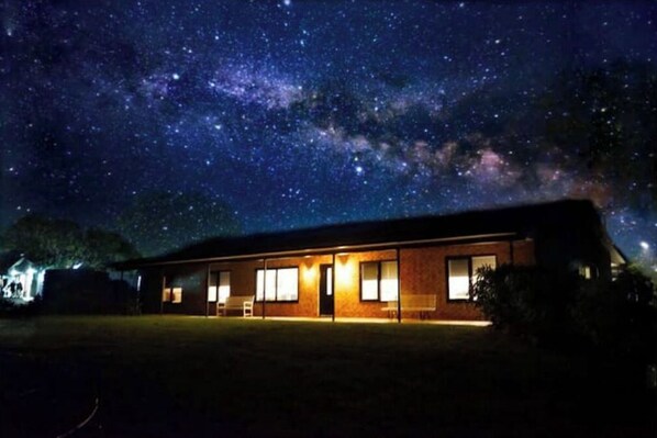 Situated in a serene grassy area, this building offers a clear view of the night sky.