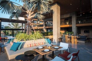 Relax in our spacious lobby with a palm tree at its center, surrounded by comfortable seating and dining areas.
