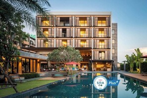 Experience the perfect blend of style and serenity at this hotel, featuring a rooftop pool surrounded by lush greenery and comfortable lounge chairs.