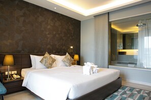 Relax in a spacious room with a large bed, bedside table, and en-suite bathroom featuring a shower area.