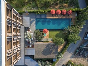Enjoy a rooftop pool experience surrounded by lush greenery and a unique balcony with a geometric design.