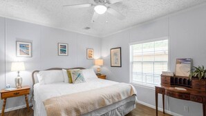 Ein Schlafzimmer mit einem Bett, Nachttischen, einem Schreibtisch und einem Deckenventilator.